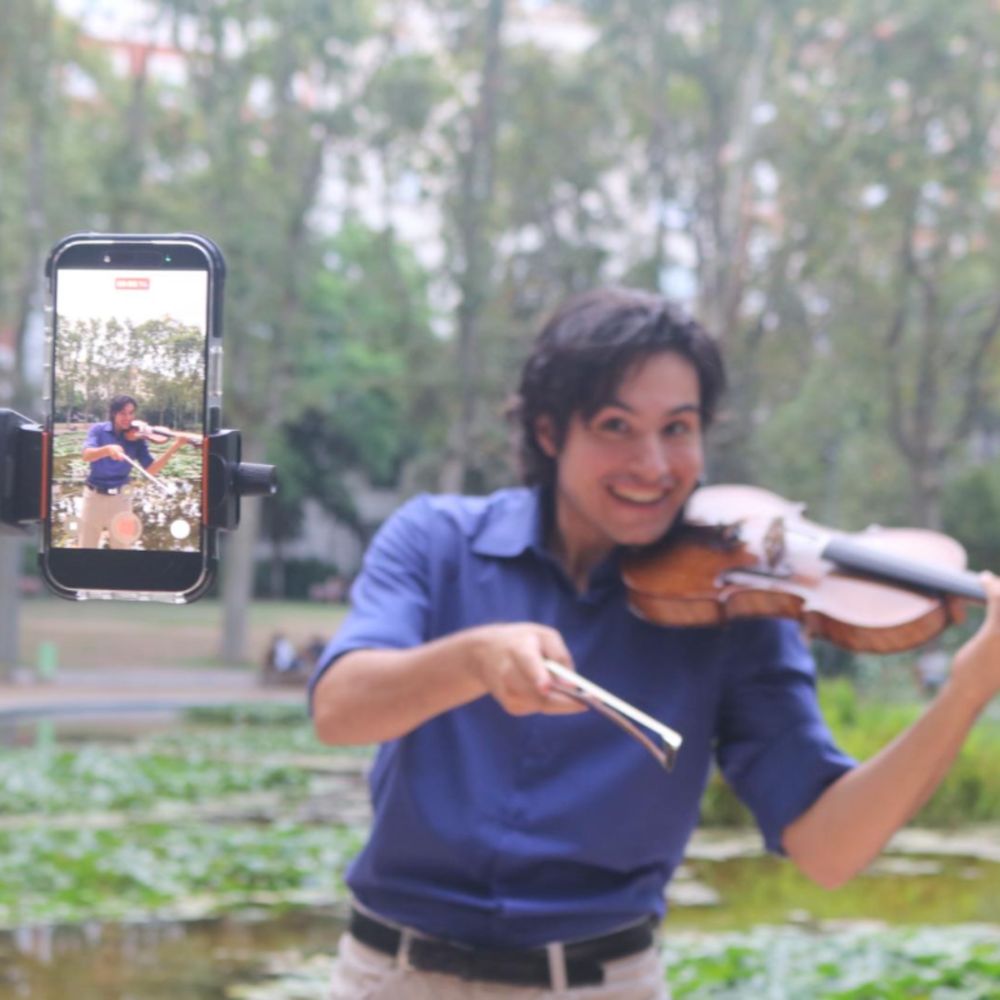 Arnau grabándose mientras toca el violín en un parque de Barcelona